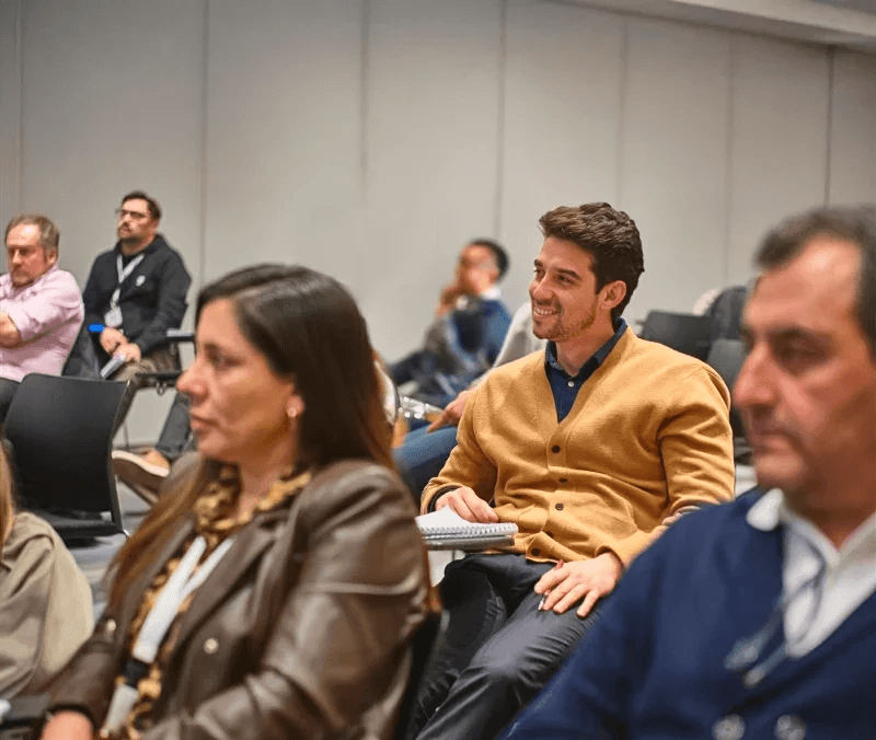 Asistentes siguiendo una sesión en sala, uno de ellos tomando notas